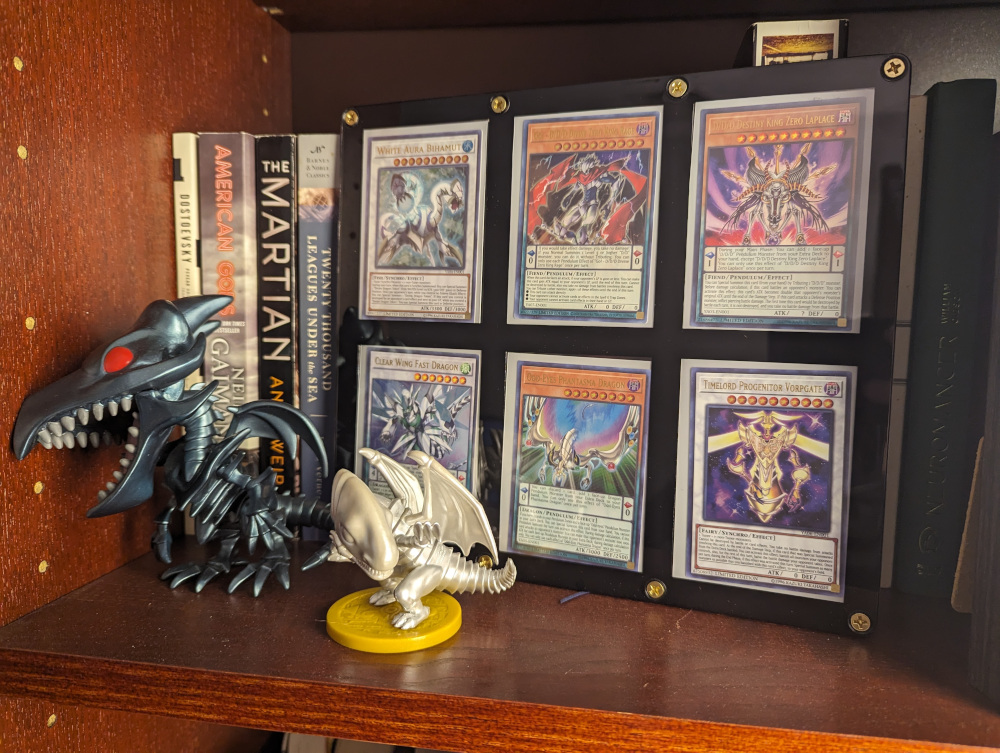 My prized collection of Yu-Gi-Oh! ARC-V manga exclusive cards, next to figures of Red Eyes Black Dragon and a miniature Blue Eyes White Dragon.